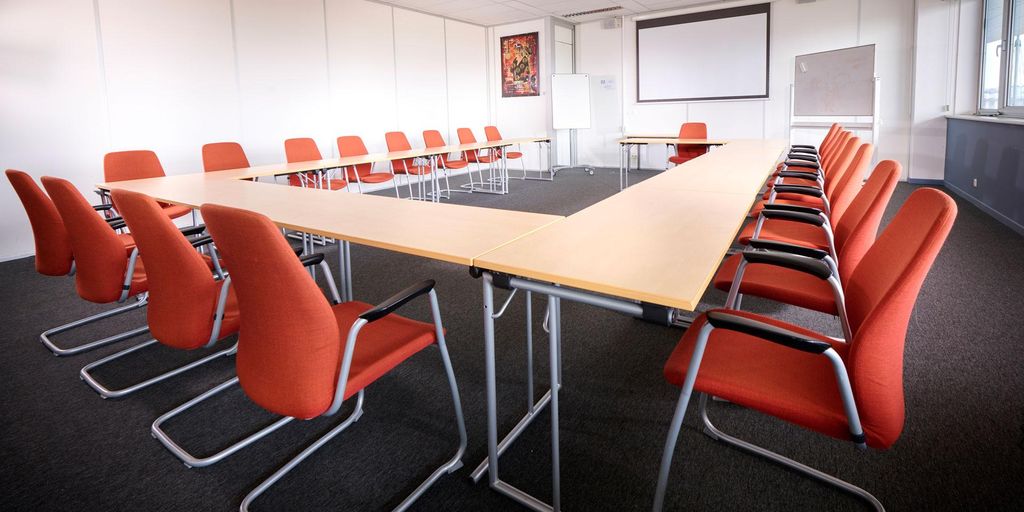 Conference room with orange chairs arranged around a central table.