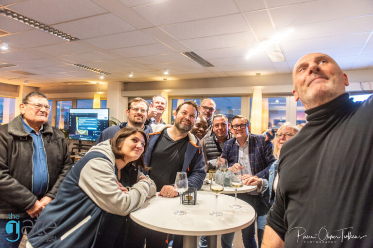 Group of people gathered around a table, smiling and socializing.